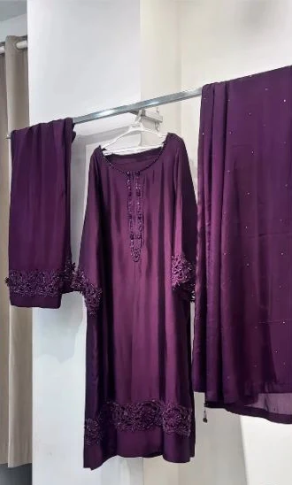 Finished plum outfit hanging in the studio, with matching lace details and embellished dupatta